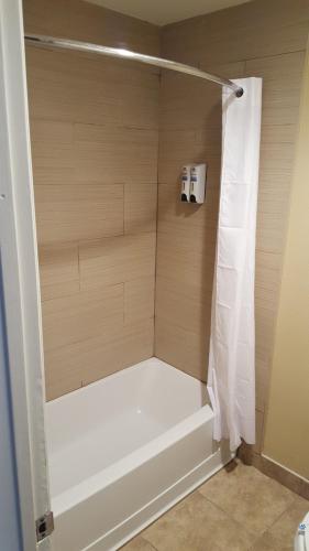 a shower with a white tub in a bathroom at Anaheim Astoria Inn & Suites in Anaheim