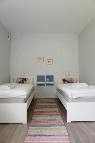 two white beds in a room with a rug at Jädra Gårdshotel in Enköping