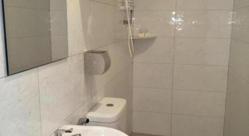 a white bathroom with a toilet and a mirror at Hotel Pangkor Mutiara in Pangkor