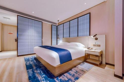 a large bedroom with a large bed and a desk at Echarm Hotel Guizhou Xingyi Jushan Avenue in Xiawutun