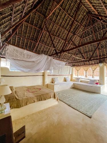 a bedroom with a bed in a straw roof at La Joya Lamu in Shela