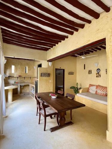 a living room with a wooden table and a bed at La Joya Lamu in Shela