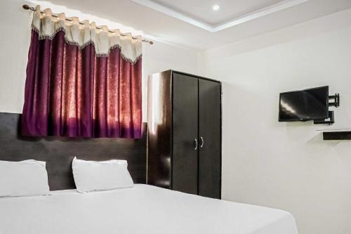 a bedroom with a bed and a cabinet with a tv at Hotel O Raj Vihar in Mohammadnagar