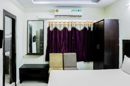 a room with two chairs and a window with purple curtains at Hotel O Raj Vihar in Mohammadnagar