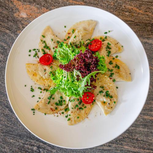 a white plate of food with a salad on it at Gartenhotel Maria Theresia in Hall in Tirol