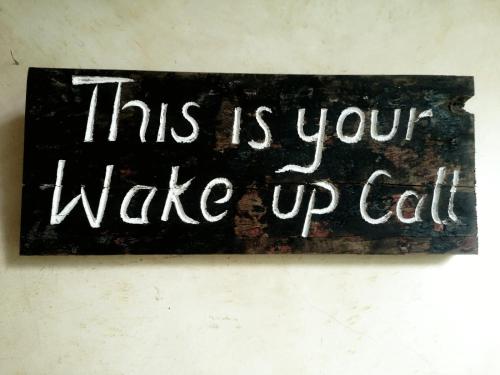 a sign that says this is your wake up call at La Joya Lamu in Shela