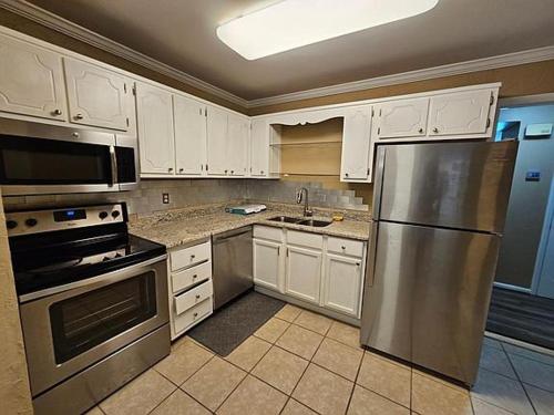 a kitchen with white cabinets and a stainless steel refrigerator at Charming Contemporary Home in Vestavia Hills