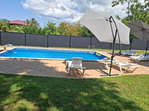 a swimming pool with a white umbrella and two chairs and a pool at phranta in Gonio