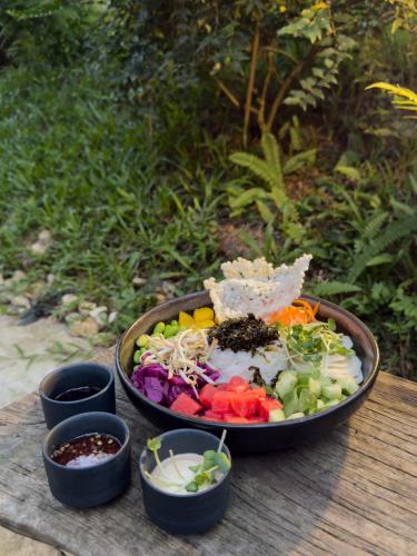 a bowl of salad on a table with bowls of food at AMAYA HOME - Lodge, Spa & Restaurant in Hanoi