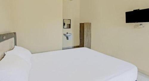 een witte kamer met een bed en een tv bij Hotel O Anartha Residence in Tegal