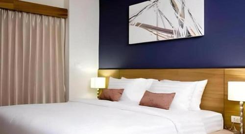 a bedroom with a large white bed with a blue wall at Pannapat Place in Bangkok