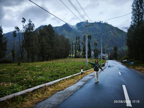 a person walking down a road with their arms out at Tengger Bromo Villa in Ngadisari