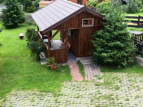 a small wooden building with a roof on a yard at Penzion 103 in Železná Ruda