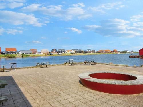 a group of benches and a fire pit next to a body of water at 7 person holiday home in Ulfborg-By Traum in Thorsminde
