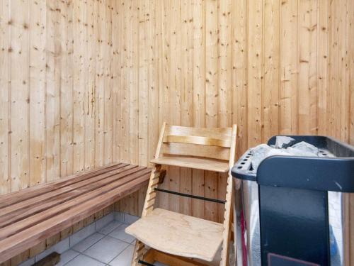 a wooden bench with a chair and a trash can at 7 person holiday home in Ulfborg-By Traum in Thorsminde