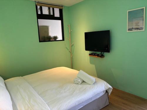 a bedroom with a bed and a flat screen tv at Playful House in Kenting