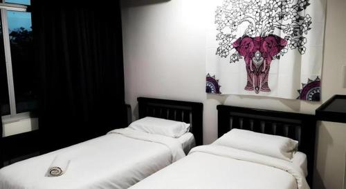 two beds in a room with a picture of an elephant at De Chukai Hotel in Cukai