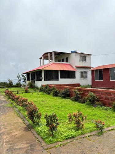 a building with a yard with plants in front of it at Silver Oak Mahabaleshwar in Mahabaleshwar
