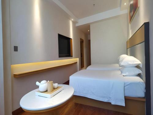 a hotel room with a bed and a table with a tv at GreenTree Inn Geermu Walking Street Business Hotel in Golmud