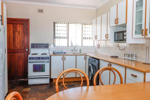 a kitchen with white cabinets and a table with chairs at Natspat 14 in Margate