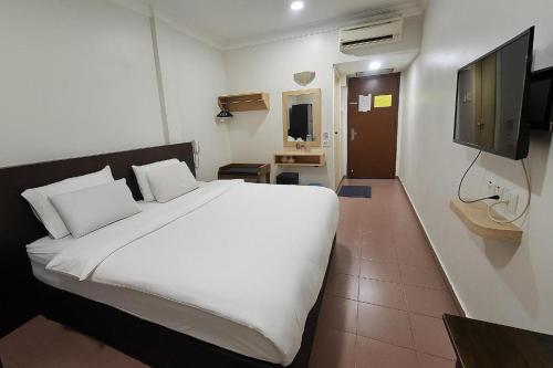 a bedroom with a white bed and a flat screen tv at G Six Hotel in Sitiawan