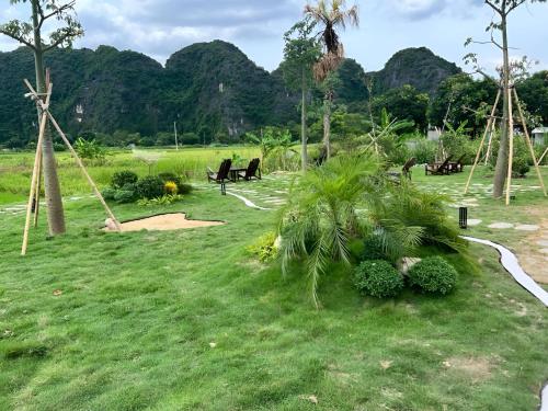 a park with benches and palm trees in the grass at Tam Coc Horizon Retreat in Vũ Lâm