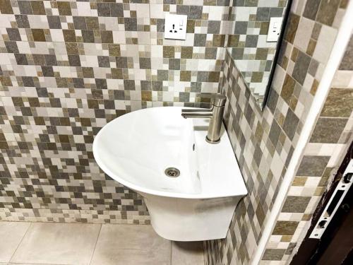 a bathroom with a white sink in a tiled wall at Estben Guesthouse in Janman