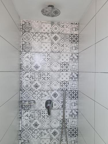 a shower with a tile wall with a faucet at Sunset Apartments & Studios in Limenaria