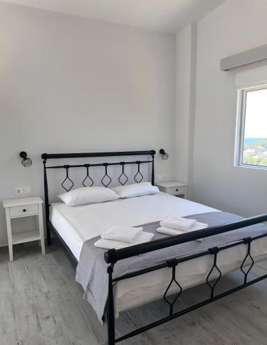 a bedroom with a black bed with white sheets and a window at Sunset Apartments & Studios in Limenaria