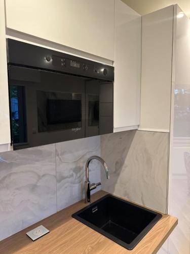 a kitchen with a sink and a microwave at New, modern and bright studio in Neuilly-sur-Seine