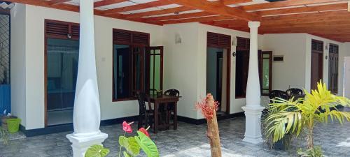 a house with a porch with columns and plants at Bakery Family Guest House in Mirissa