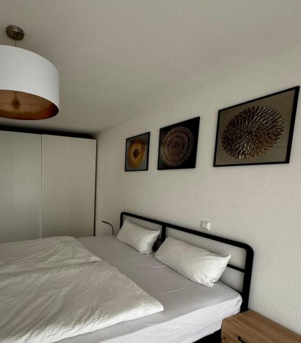 a bedroom with a bed with four pictures on the wall at AIL Kün Studio in Künzelsau