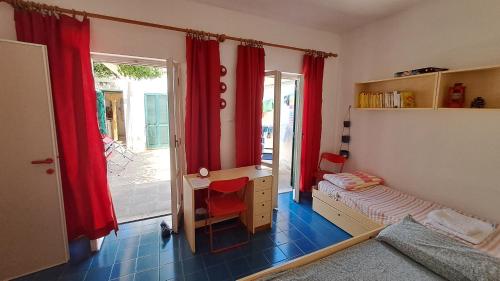 a bedroom with a bed and a desk and a window at Casetta nel Villaggio Conca Specchiulla in Conca Specchiulla