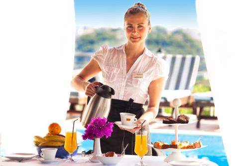 a woman standing at a table with a tray of food at Vigles Sea View, Philian Hotels and Resorts in Skiathos Town