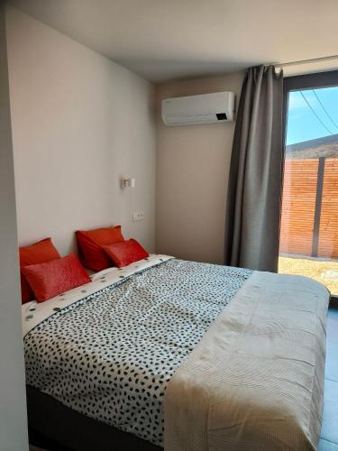 a bedroom with a bed with red pillows and a window at Vakantiewoning De Woestijn - Den Ast in Roosdaal