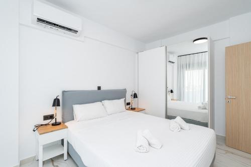 a white bedroom with a white bed and a mirror at Emerald Island Residential Complex in Skala Rachoniou