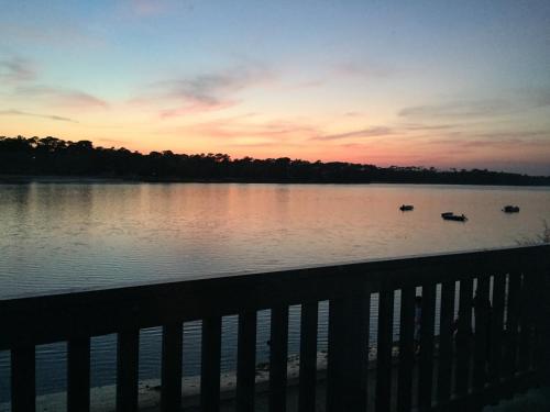 a sunset over a lake with two boats in the water at Appartement Du Lac in Hossegor