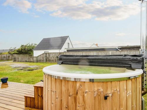 a hot tub on a deck with a house in the background at Luxury Spa Retreat in Thorsminde - By Traum Ferienwohnungen in Ulfborg