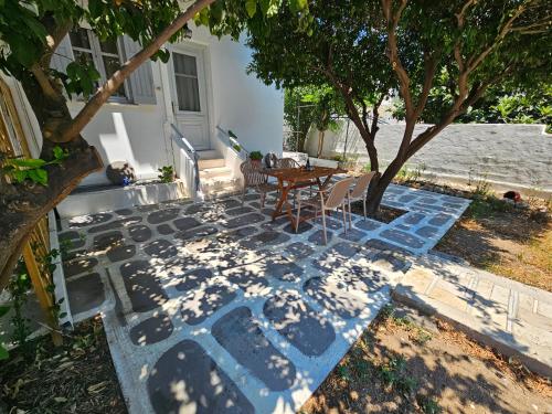 a patio with a table and chairs under a tree at Lemon Nest 2 in Votsalákia