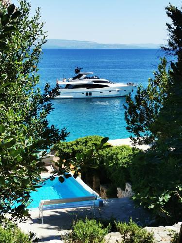a boat in the water with a swimming pool at Beach House Bella Vista apartments in Trogir