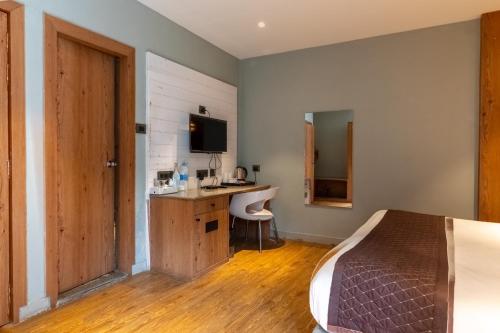 a bedroom with a bed and a desk and a television at Kava Suites Namchi in Namchi