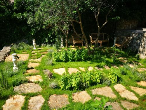 a garden with a stone pathway with chairs and trees at Beach House Bella Vista apartments in Trogir