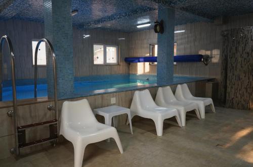 a row of white chairs in front of a swimming pool at Aquasalis in Câmpulung Moldovenesc