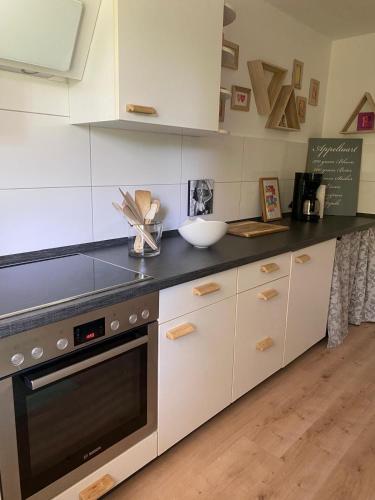 una cucina con mobili bianchi e un piano di lavoro nero di Beach & Birds a Hohenfels