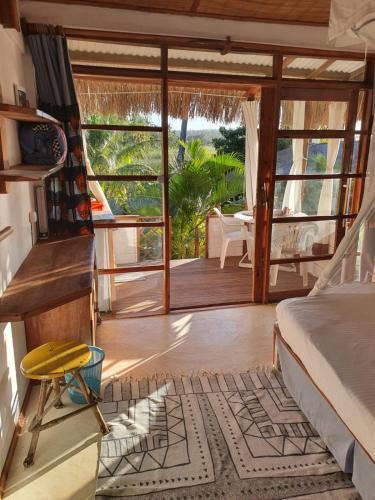 a bedroom with a bed and a balcony with a table at Sunset View Tofo in Praia do Tofo