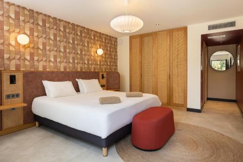 a bedroom with a large white bed and a red stool at Mercure Brignoles Golf de Barbaroux & Spa in Brignoles