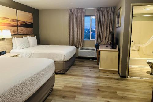 a hotel room with two beds and a bath tub at Days Inn by Wyndham Seatac Airport in SeaTac