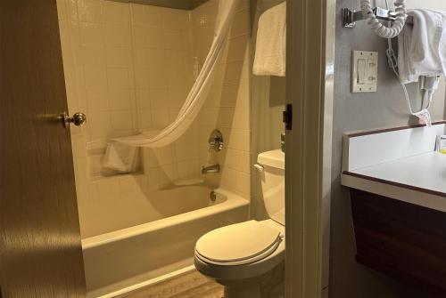a bathroom with a toilet and a tub and a sink at Days Inn by Wyndham Seatac Airport in SeaTac