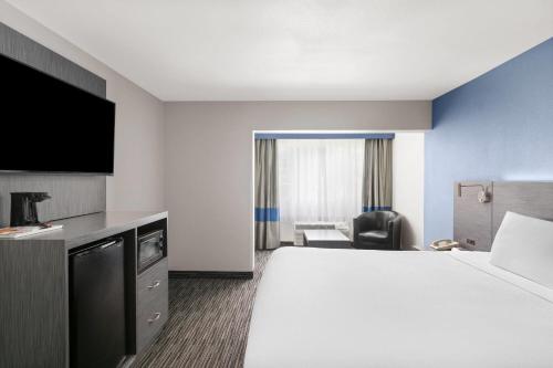 a hotel room with a large bed and a chair at Travelodge Inn & Suites by Wyndham Anaheim on Disneyland Dr in Anaheim