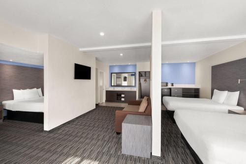 a hotel room with two beds and a couch at Travelodge Inn & Suites by Wyndham Anaheim on Disneyland Dr in Anaheim
